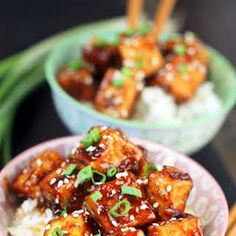 two bowls filled with tofu and rice on top of a table