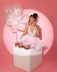 a woman sitting on top of a white box with balloons in the shape of flowers