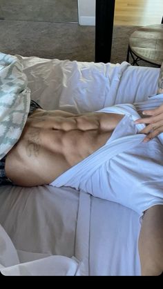 a shirtless man laying on top of a bed