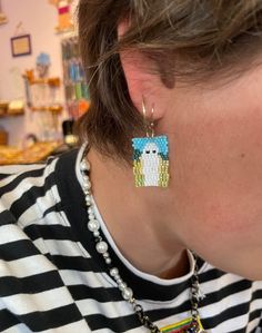 a close up of a person wearing a pair of earrings with bead designs on them