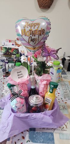 a mother's day gift basket on a table with balloons and confetti