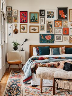 a bed sitting in a bedroom next to a wall with pictures on it and a chair