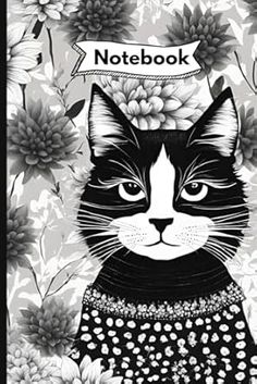 a black and white cat with flowers on it's head sitting in front of a notebook