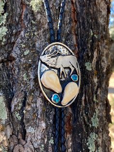 a necklace with an animal on it hanging from a tree