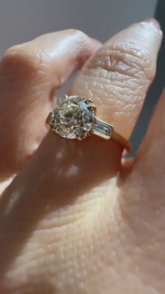 a woman's hand holding an engagement ring with two baguettes on it