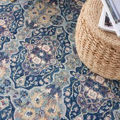 a blue rug with an intricate design on the floor next to a wicker basket