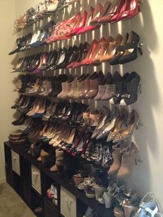 there are many pairs of shoes hanging on the wall in this shoe storage area,