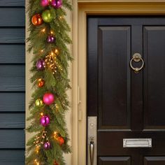 a christmas garland on the front door of a house decorated with ornaments and baubles