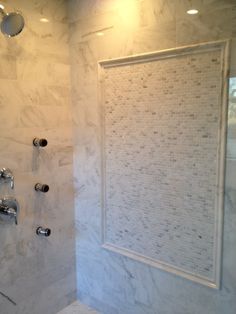 a bathroom with marble walls and flooring, shower head and hand held faucet