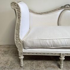 a white couch sitting on top of a wooden floor next to a wall with a mirror above it