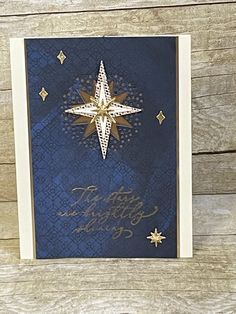 a blue and gold christmas card with a snowflake on the front, stars in the background