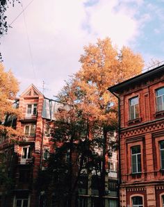 an old brick building with many windows and balconies on the top floor is surrounded by trees