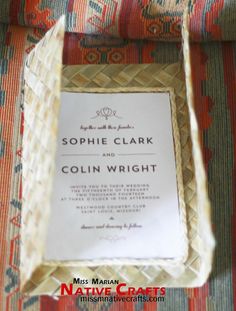 a wedding program in a box on a chair with an orange and red striped pillow