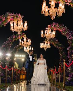 a bride and groom walk down the aisle at their wedding reception in front of chandeliers