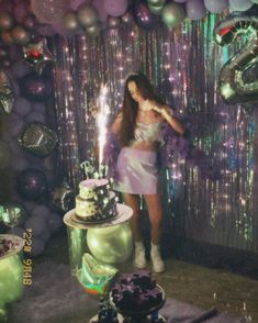 a woman standing in front of a cake and balloons