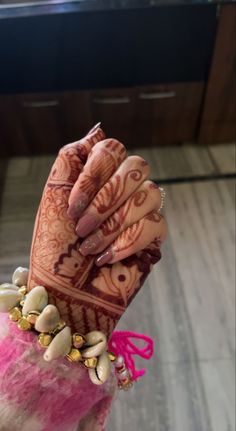 a woman's hands with henna and jewelry on top of her arm,