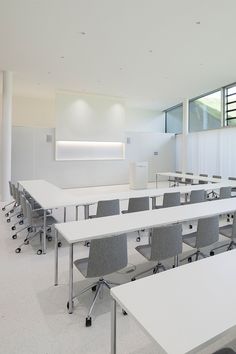 an empty classroom with desks and chairs in the middle, near a white wall