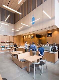 people are sitting at tables in an open area with bookshelves on the walls