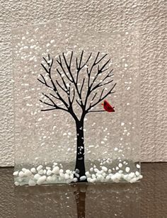 a red bird sitting on top of a tree with white rocks in front of it