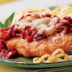 chicken parmesan with pasta and sauce on a green plate, ready to be eaten