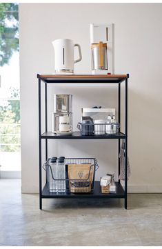 a shelf with baskets, cups and mugs on it in front of a white wall