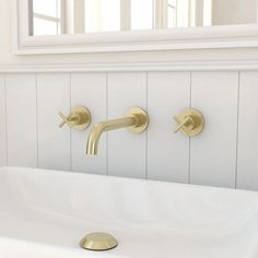 a bathroom sink with two faucets and a mirror in the back wall behind it