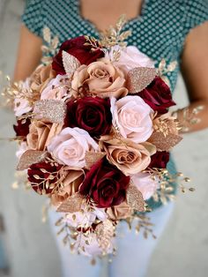 a bridal bouquet with red and pink flowers in it is held by a woman