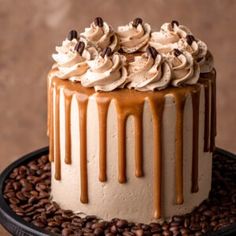 there is a cake on the table with coffee beans around it and drizzled in caramel