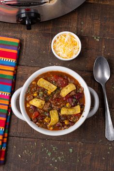 a bowl of chili with cornbreads and cheese on the side