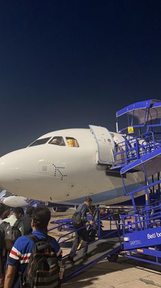 an airplane being loaded with luggage and people standing on the stairs next to it that are attached to another plane