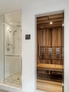 a bathroom with a wooden sauna in the shower and glass doors on both sides