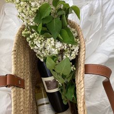 a wicker basket filled with wine bottles and flowers