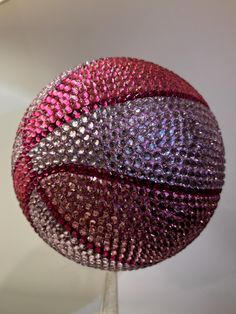 a red and purple ball on a stand with white background in the foreground, it appears to be sequins