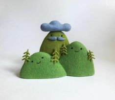 three green rocks with trees and clouds on them, one is made out of felt