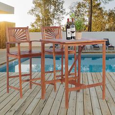 an outdoor table with two chairs next to a pool