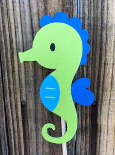 a green and blue sea horse on a wooden fence with it's tail sticking out