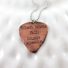 a wooden guitar pick that says when words fall, music speaks on the inside of it