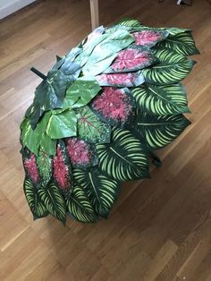 an umbrella that is on the ground with leaves and flowers painted on it's side