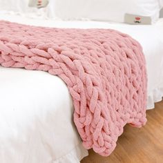 a pink blanket sitting on top of a white bed