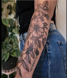 a woman's arm with flowers and leaves on it