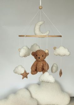 a teddy bear sitting on top of a cloud mobile