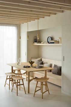 a living room with a couch, table and chairs next to a wall mounted bookshelf