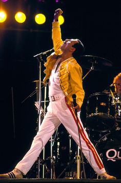 elvis presley performing on stage in front of microphones and drum sticks with his arms up