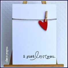 a white card with a red heart hanging on a clothes line and the words i just love you