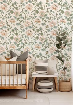 a baby's room with floral wallpaper and a crib in the foreground