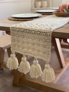 a crocheted table runner with tassels hanging from it