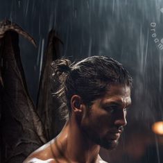 a shirtless man standing in the rain with an umbrella over his head and two bats behind him