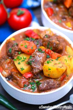 two bowls filled with stew and vegetables on top of a blue cloth next to tomatoes