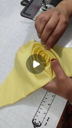 someone is working on something that looks like a yellow ribbon with a rose in it