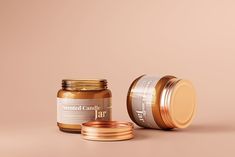 an open jar of peanut butter next to two gold lids on a pink background with the lid off